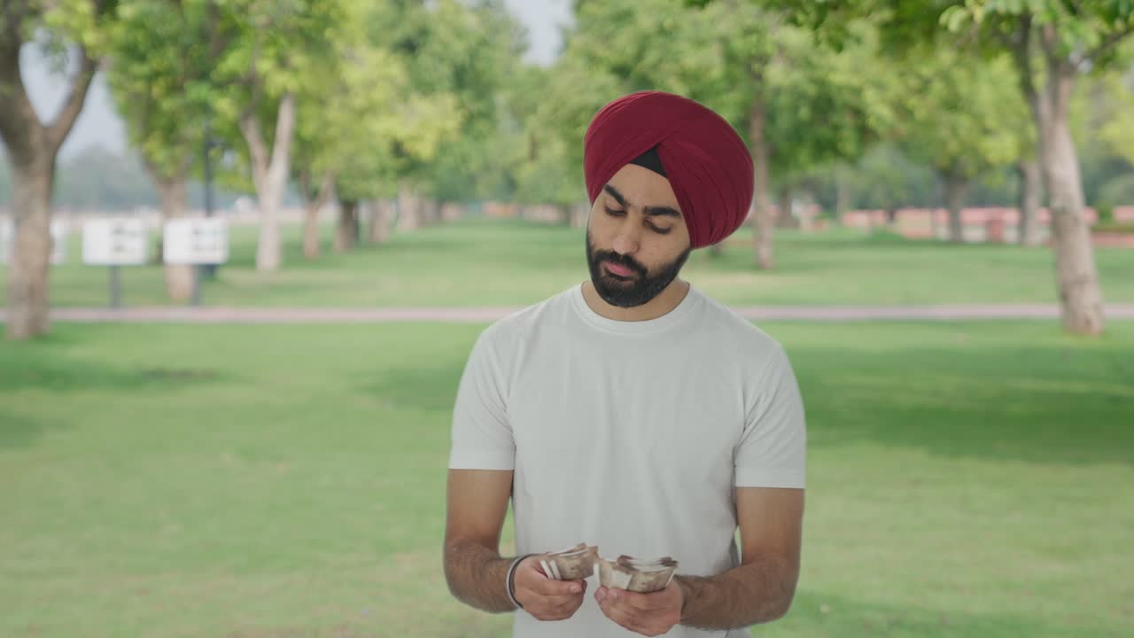 Uomo sikh indiano triste che conta denaro al parco.