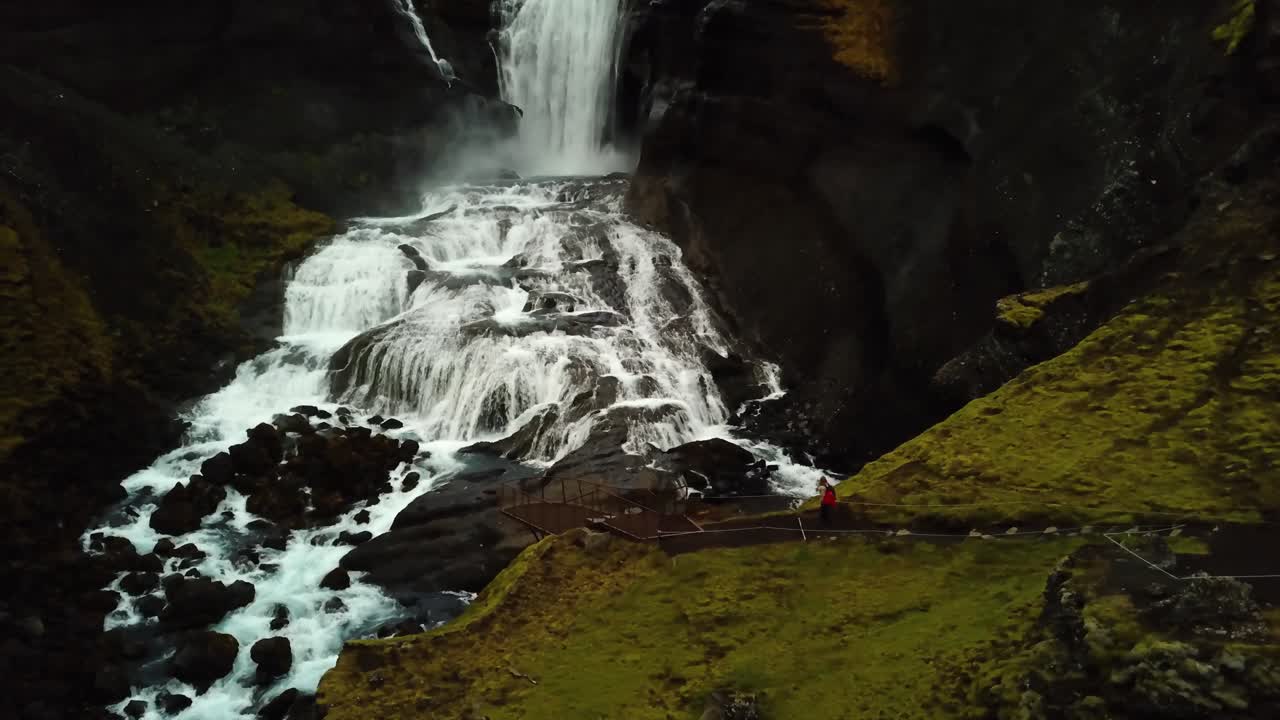 vista aérea de drones de un viajero caminando cerca de la cascada ófærufoss, en las tierras altas de islandia