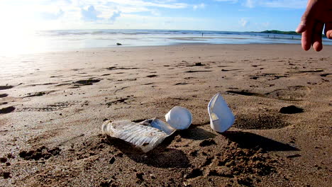 Un-Humano-Tirando-Un-Vaso-De-Papel-En-La-Playa-Con