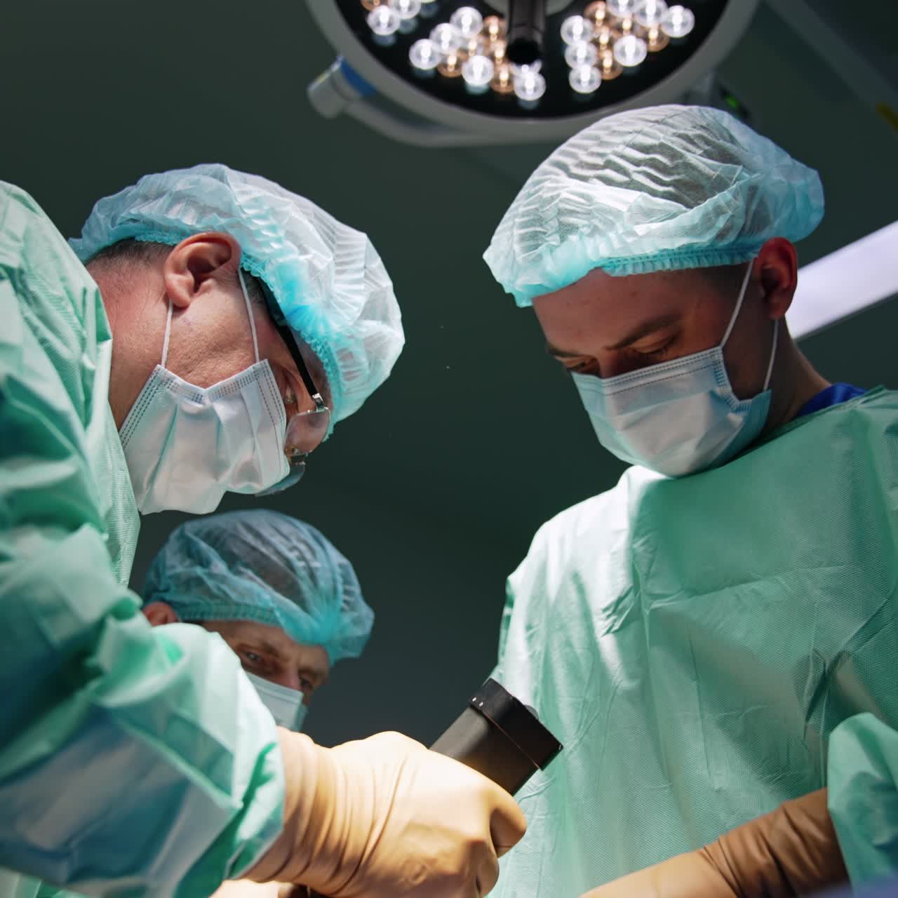 Un chirurgo adulto di sesso maschile sicuro di sé prende un dispositivo chirurgico. I dottori applicano lo strumento. Angolazione dal basso