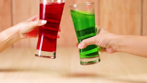 hands exchanging red and green drinks