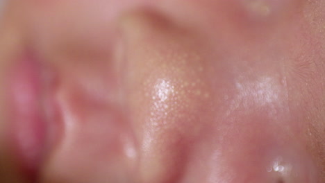 close-up shot of the reddish skin of a sleeping newborn baby showing some white spots on its nose and its pinkish cute lips