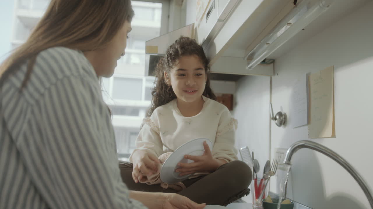Little Girl Helping Mom Do the Dishes in the Kitchen