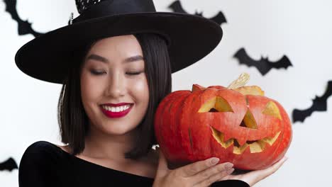 mujer feliz en disfraz de bruja con linterna de jack-o'-lanterna
