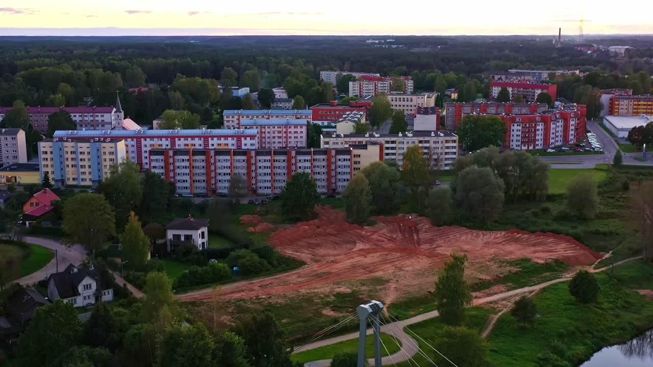 Vyčištěný stavební pozemek s okolními bytovými domy ve Valmieře, Lotyšsko, letecký pohled