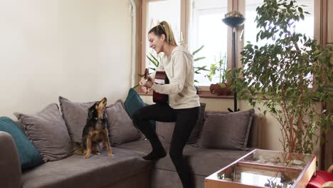 young woman playing guitar while her dog is singing