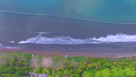 drone video looking straight down on rolling waves approaching a beautiful sandy beach in ballena bay in costa rica