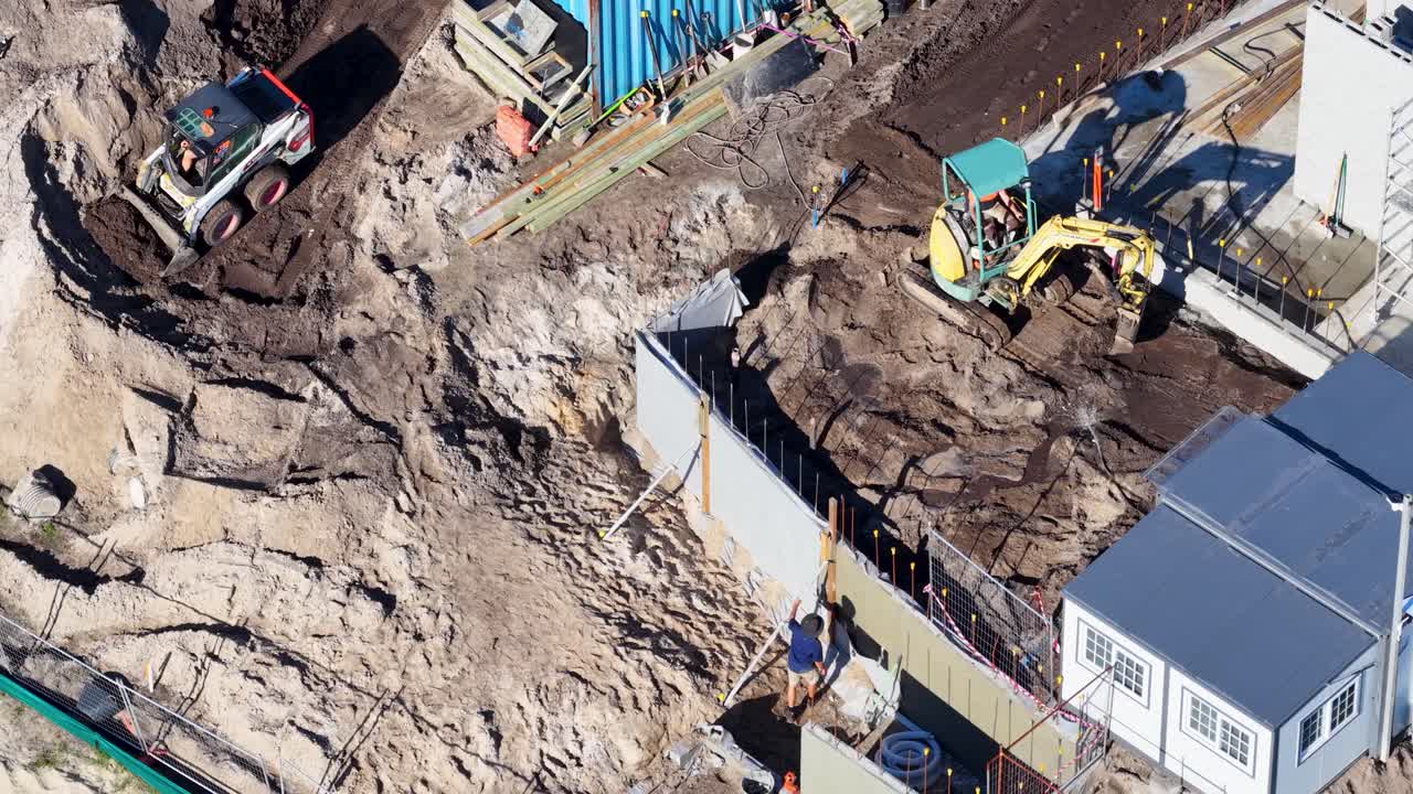 Drone footage captures workers and machinery at a construction site in Gold Coast, Australia, highlighting earthmoving and building activities