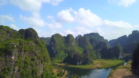cinematic drone footage of majestic green limestone peaks. ricefields in the wild jungle in the spring with boat tour canal in trang an, ninh binh, vietnam