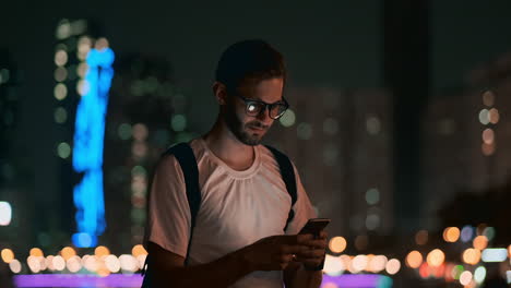 Un-Joven-Con-Gafas-Por-La-Noche-Mira-La-Pantalla-Del-Smartphone-Y-Escribe-Mensajes-De-Texto-Para-Su-Blog-En-Las-Redes-Sociales.-Lee-Información-Y-Hace-Un-Viaje-Martour