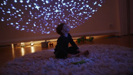 young child enchanted by star projector on ceiling
