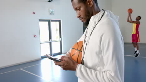 Afroamerikanischer-Trainer-überprüft-Sein-Telefon-In-Einem-Fitnessstudio,-Mit-Kopierplatz