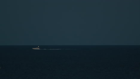 small boat moves in the night in the ocean in summer on the horizon