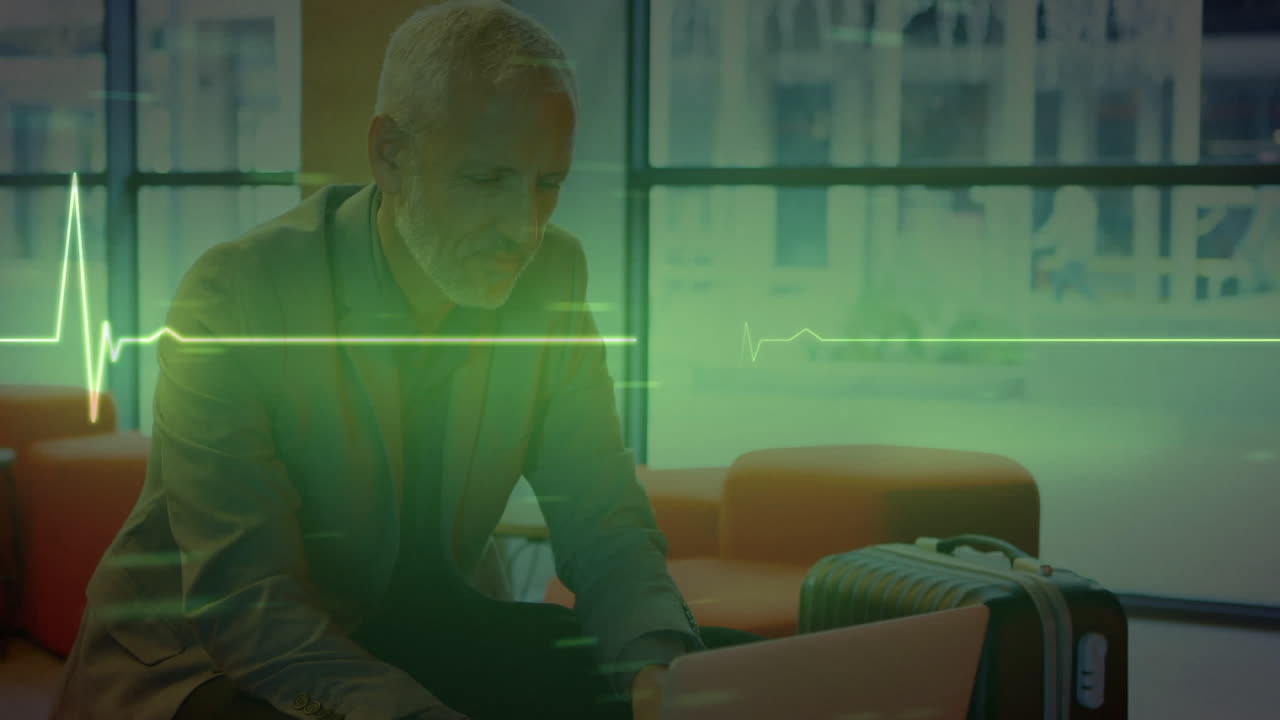 Animation of heart monitor against caucasian senior businessman using laptop at office