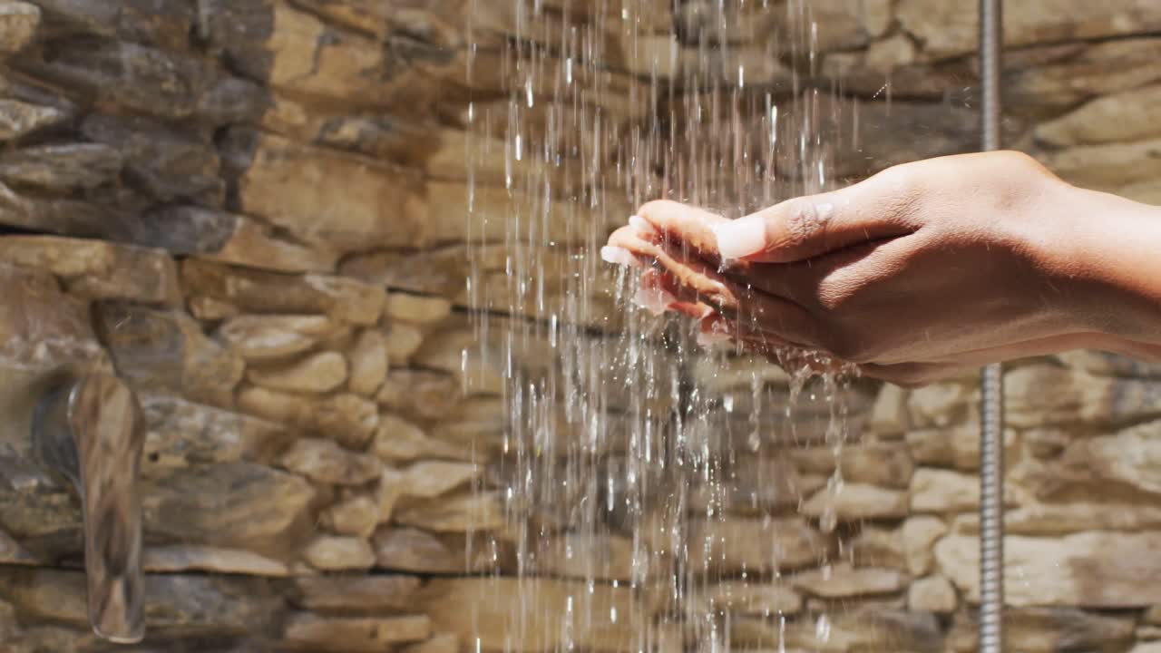 video de las manos de una mujer afroamericana duchándose con agua