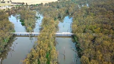 Imágenes-De-Drones-De-Un-Camión-Que-Pasa-Por-Un-Puente-De-La-Autopista-Del-Valle-De-Murray-Sobre-El-Río-De-Los-Hornos-Donde-Se-Une-Al-Río-Murray-Cerca-De-Bundalong,-Victoria,-Australia