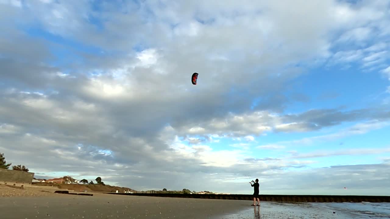 hombre volando una cometa en la playa haciendo grandes figuras de ocho
