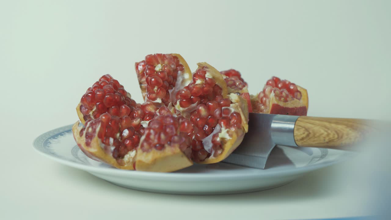 Pomegranate cut open on plate with knife showing delicious seeds