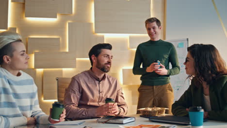 coworkers enjoy coffee break at desk conference room closeup. smiling colleagues