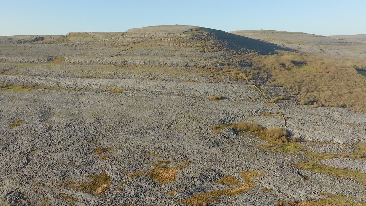 дрон отступает над террасовым скальным склоном берренской ирландии с стенами и дорогой в солнечный день