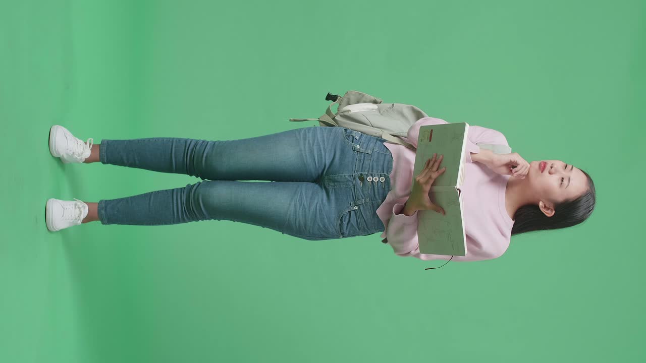 Full Body Of Asian Woman Student Reading A Book And Thinking In Green Screen Studio