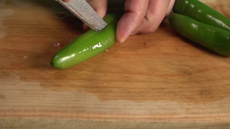 manos cortando un ají en una tabla para cortar