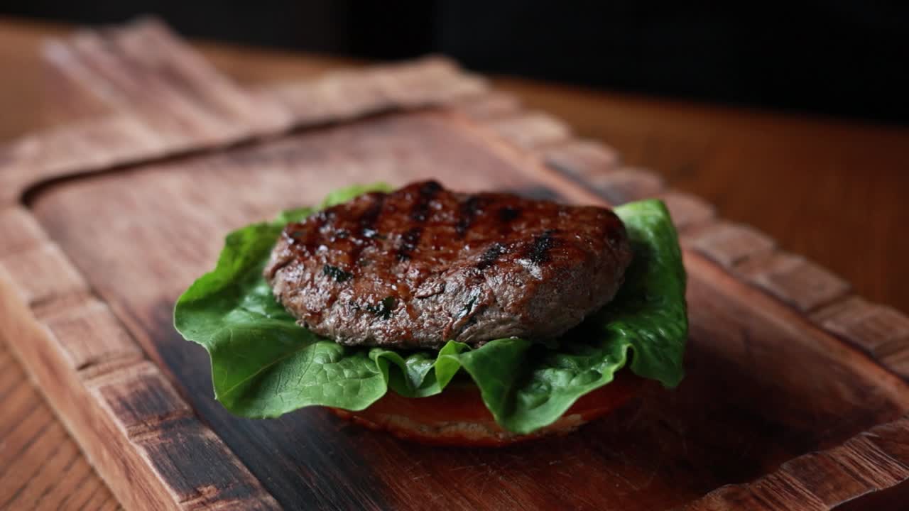 primer plano de una deliciosa hamburguesa de queso que se está preparando en una tabla de madera