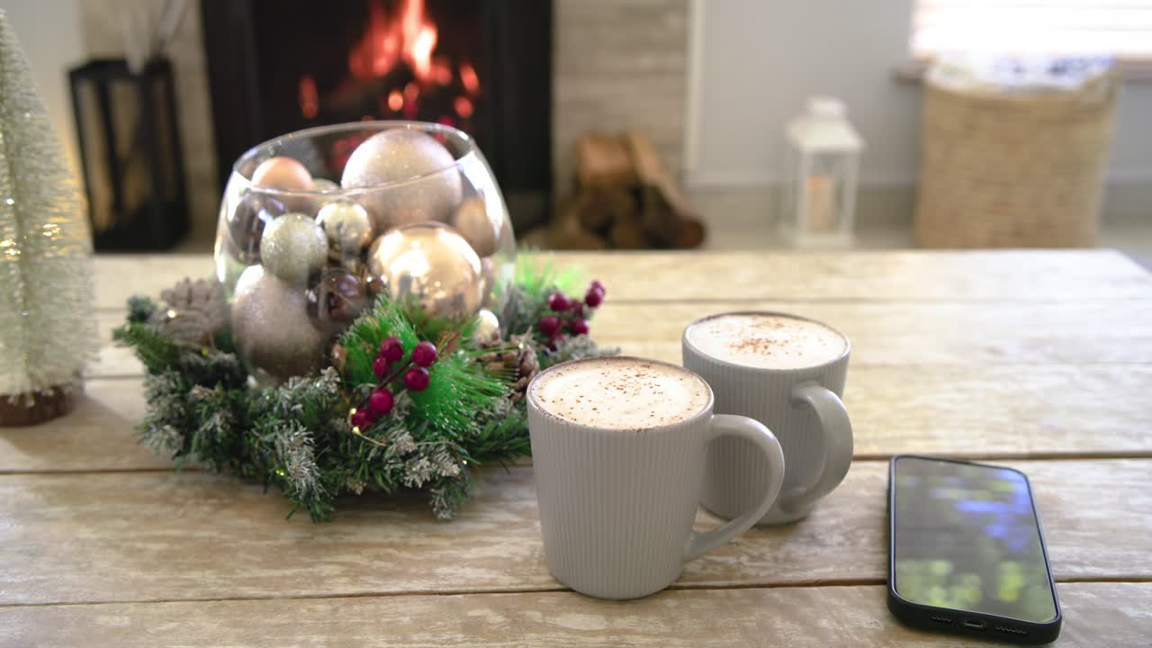 Lantern glow guiding placement of tree, wreath, mugs and phone by fireplace, forming festive scene