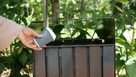 women hand throwing an empty plastic water bottle in the garbage trash or bin,