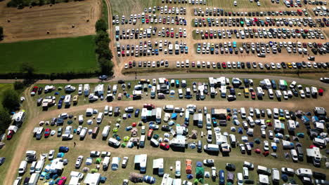 circular aerial view of full camping parking lot with green field and racing track in background at music festival