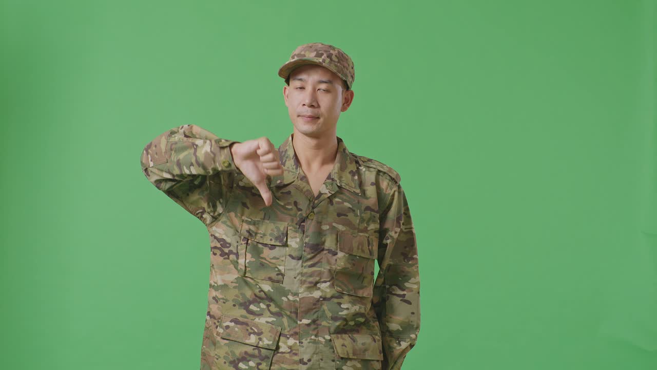 Asian Man Soldier Showing Thumbs Down Gesture To Camera While Standing In The Green Screen Background Studio