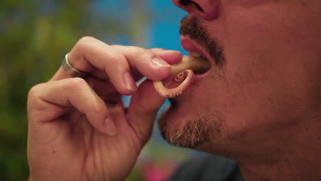 man biting and chewing octopus during dinner at the beach resort
