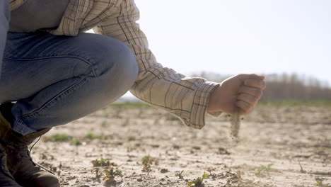 unerkennbarer mann, der sand vom boden in der landschaft aufnimmt