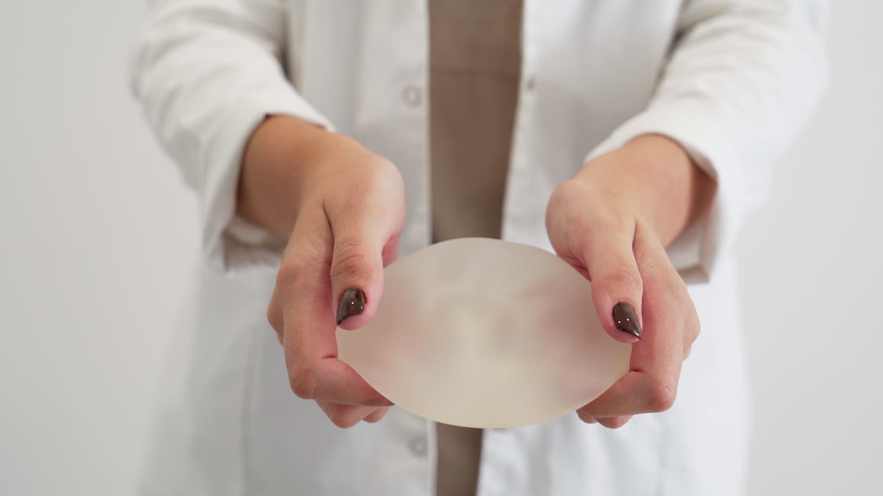 cirujano plástico demostrando la resistencia de la prótesis mamaria estirándola y apretándola
