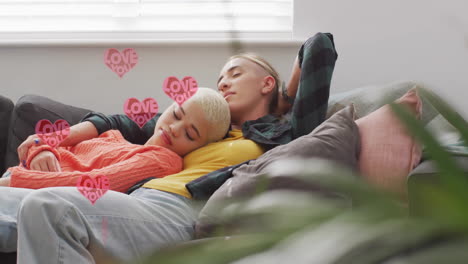 animation of hearts floating over diverse female couple sleeping