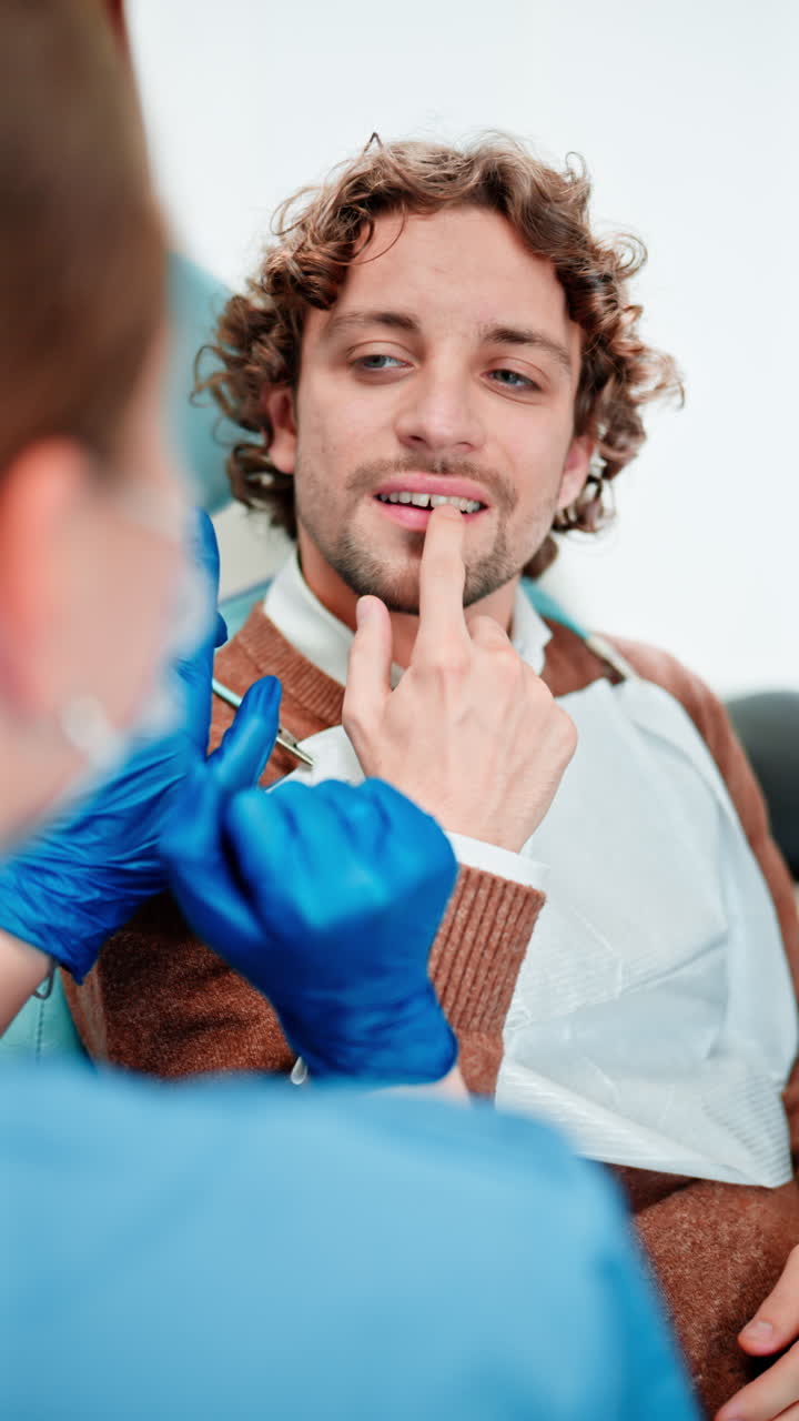 Dentist wearing a protective mask, goggles, and gloves checking the teeth of a patient in a dental cabinet. Vertical