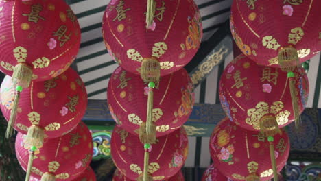 Slow-motion-tilt-shot-of-paper-Chinese-lanterns-hanging-from-roof,-daytime