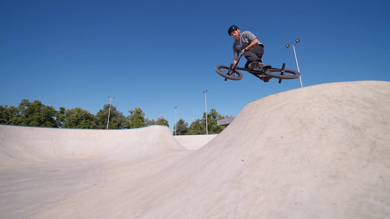 Ciclista BMX esegue un trick aereo in uno skatepark all'aperto