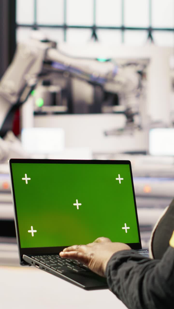 Vertical video Technician in industrial plant using green screen laptop to diagnose equipment