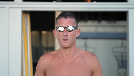 young attractive swimmer puts on his swimming goggles frontal close up