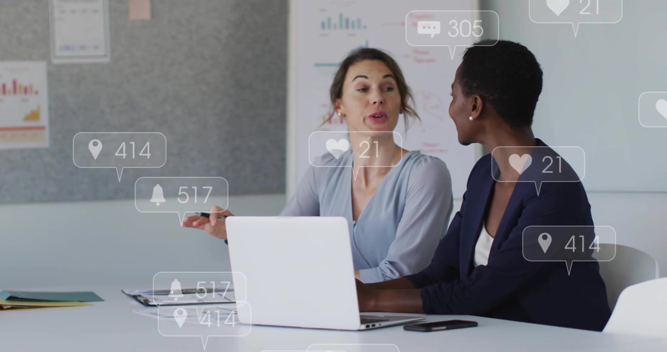 Duo di marketing al lavoro, la donna a destra digita e i 'mi piace' aumentano sul laptop per la revisione della campagna.