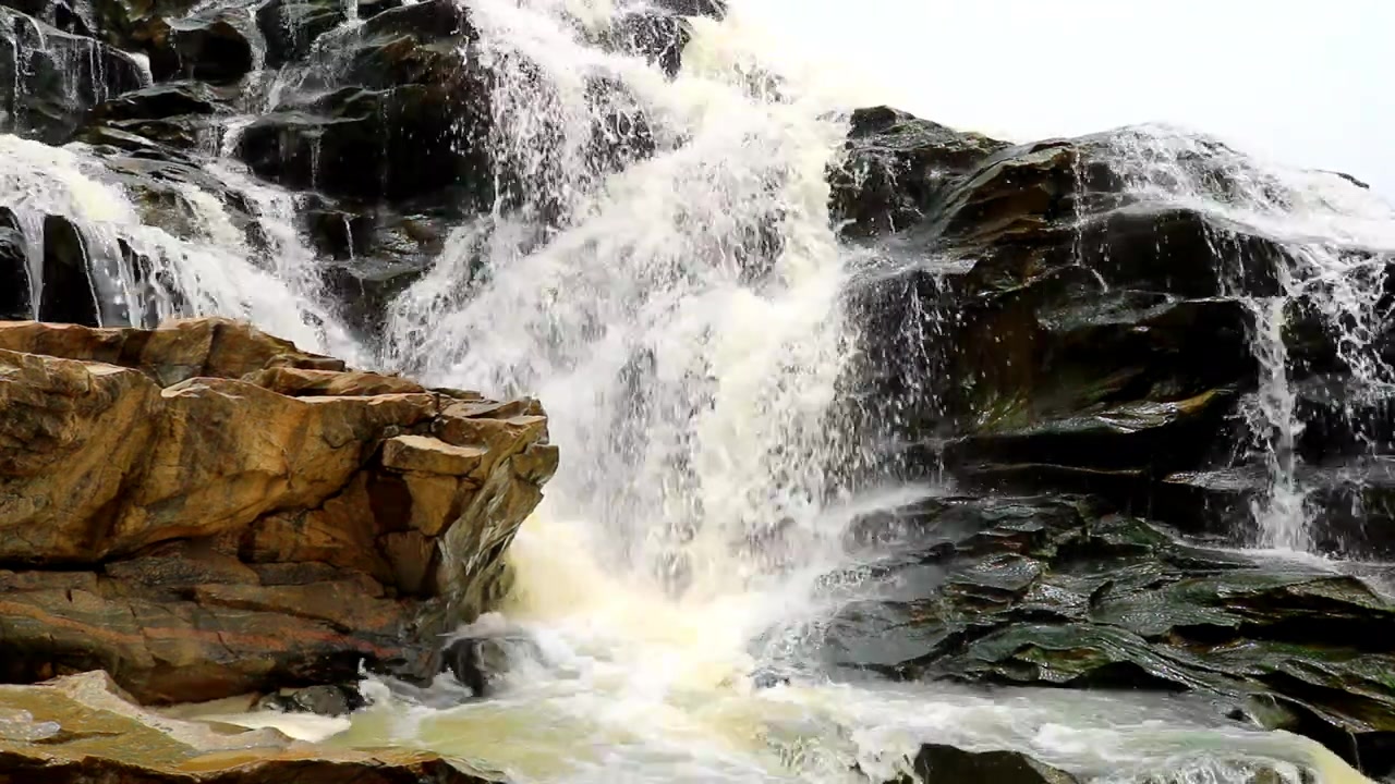 Camera: Close up, No Pan: African furious multi-point waterfalls splashes down the rocky hillside to create amazing view.
