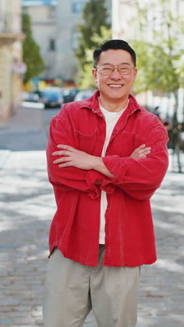 happy asian man smiling turning looking at camera resting good news feel satisfied on city street