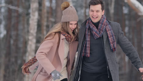 young married couple in love walking in the winter forest. a man and a woman look at each other laughing and smiling in slow motion. valentine's day love story.