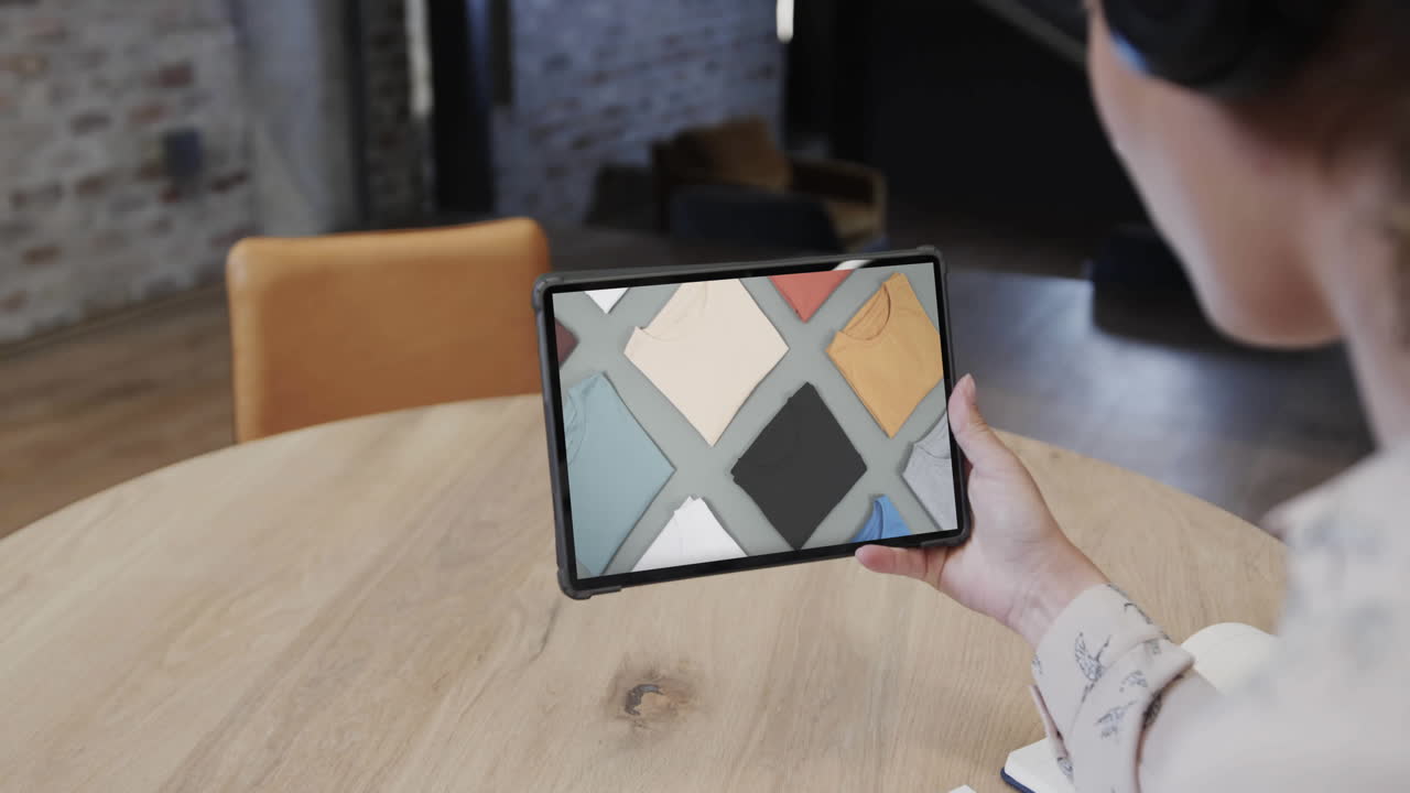 Biracial woman using tablet at cafe online shopping for clothes, slow motion