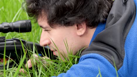 Young-hunter-on-the-ground,-aiming-for-pray-with-a-black-hunting-rifle-weapon