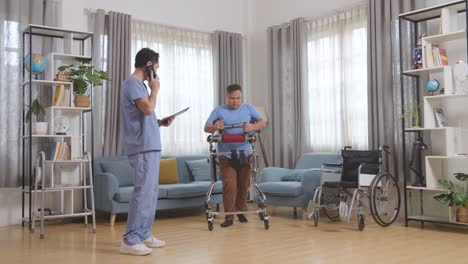 full body of asian male nurse with a tablet talking on smartphone while watching a patient using walker to walk by himself during a physical therapy at home