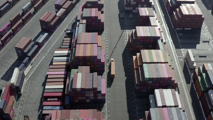 Aerial view following truck vehicle moving through import export shipping containers distribution storage depot