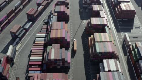 aerial view following truck vehicle moving through import export shipping containers distribution storage depot