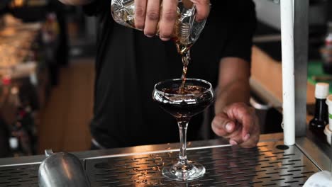 black manhattan being poured into a glass in slow motion